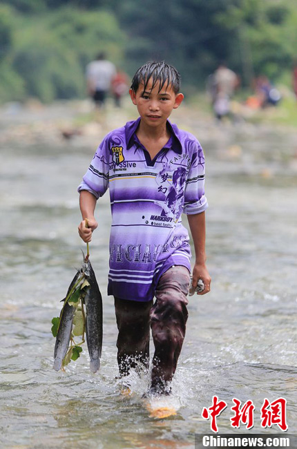 圖為7月9日，一名男孩在鬧魚節(jié)活動(dòng)中抓到了兩條魚。譚凱興 攝