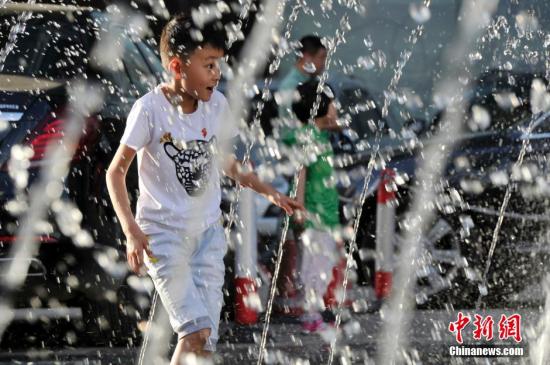 山西太原最高溫36℃,兒童在噴泉周圍戲水消暑。