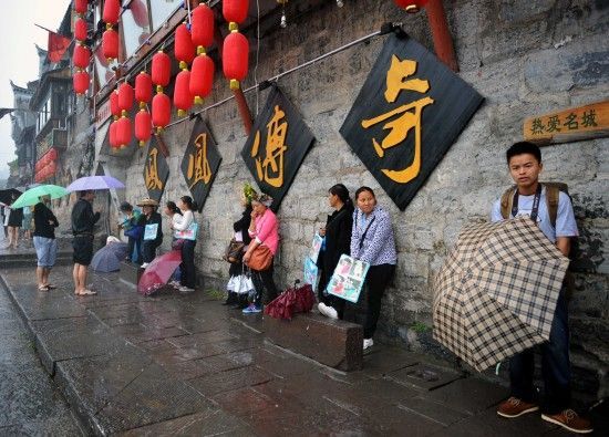 　4月29日上午11時(shí)20分，一些游客和古城當(dāng)?shù)氐木用穸阍谝粋€(gè)酒吧的屋檐下避雨。這些當(dāng)?shù)鼐用褚詾橛慰团恼罩\生，一場(chǎng)降雨讓他們的生意更加清淡。