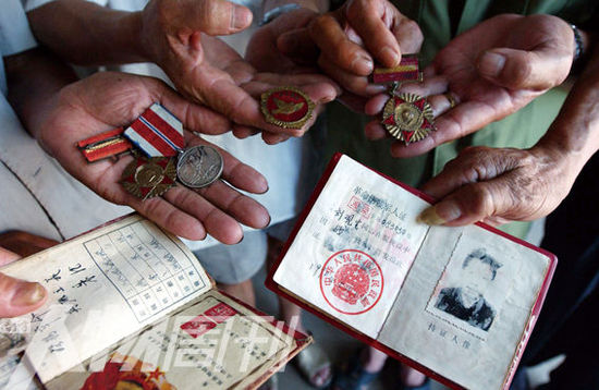 幾位志愿軍老兵展示自己的立功證、傷殘軍人證與勛章