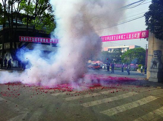 市民在普洱市主干道振興大道的金孔雀交通運(yùn)輸集團(tuán)有限公司門前燃放鞭炮，公司門前掛著“貪腐份子沈培平被查處，罪有應(yīng)得，大快人心?！钡臈l幅