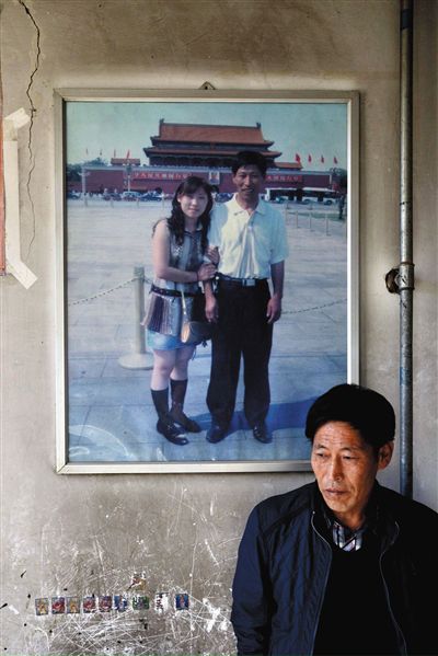 11月14日，承德市平泉縣，潘小梅父母的家，潘小梅父親靠在墻上，身后掛著數(shù)年前他和潘小梅在北京的合影照片。新京報(bào)記者