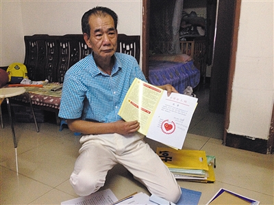 翻出一家網(wǎng)站贈予的“中國好人”證書，區(qū)少坤單膝跪在地上，“你看，我是中國好人啊?！?范春旭 攝