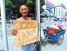 老人舉著牌子在路邊等候失主。京華時(shí)報(bào)記者譚青攝