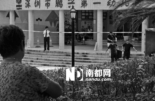 →7月19日，鵬興花園第一幼兒園門前，民警在現(xiàn)場進行完勘查取證后，園長和保安的尸體被運走。南都記者 徐文閣 攝