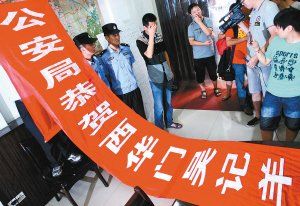面對(duì)警方收繳的條幅，老板楊某也不好意思地用手遮擋臉