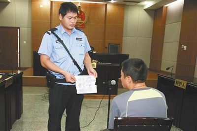 昨日庭審中，法警向趙某出示其扎完車(chē)胎后所留辱罵公司的紙條。通訊員 李秀文 攝