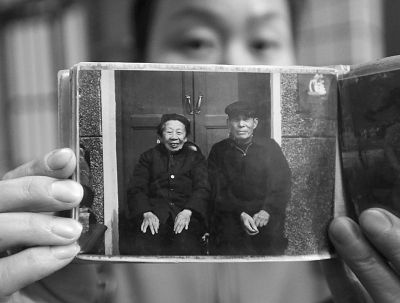 圖為孫女拿出兩位老人上世紀(jì)80年代在家門口的合影給記者看。記者楊濤 攝