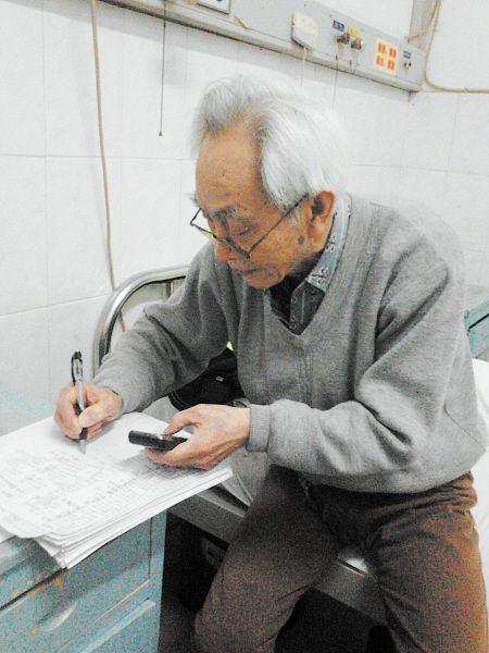杜修源老人埋頭寫著特殊的“日記”。 李卓 攝