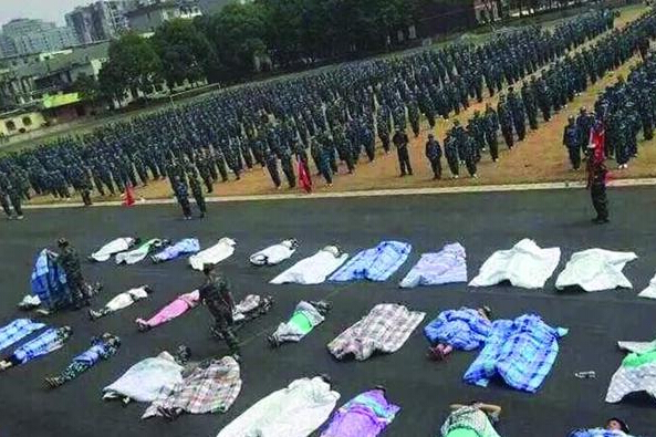 20多名女生躺在瀝青跑道上，身上嚴(yán)嚴(yán)實(shí)實(shí)地裹著棉被，接受太陽的照曬。