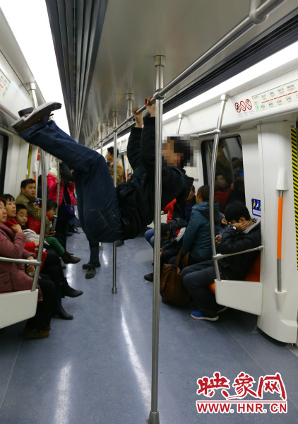 地鐵試乘日，一男子在車廂內(nèi)攀爬扶手自?shī)首詷?lè)