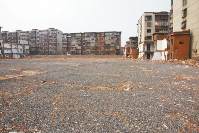 為降塵，旮旯王村拆遷后裸露的地面上鋪了一層石子。