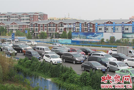 記者看到鄭州機(jī)場(chǎng)收費(fèi)站口車(chē)輛排隊(duì)，與此形成鮮明對(duì)比的是，路的對(duì)面（另一半幅）卻車(chē)輛較少，通行順暢。