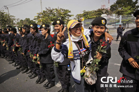 2013年12月03日,曼谷總理府與曼谷警署允許反政府示威民眾進(jìn)入,雙方進(jìn)入暫時(shí)“停戰(zhàn)”狀態(tài)迎接泰王生日。曼谷警察總署,女警們手持鮮花送給反政府示威民眾。圖片來源:Manish Swarup/東方IC