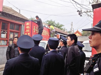昨日下午,東城區(qū)工商、城管、公安等部門,對雍和宮附近的預(yù)測中心進行清理整頓,站在車頂?shù)膬擅と苏鸪患摇邦A(yù)測中心”的招牌。因雍和宮、白云觀等文化景點外聚集大量算命先生,被媒體稱為“算命一條街”。本版攝影/新京報記者 李寧 攝