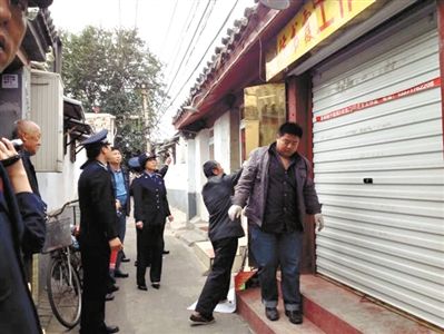 執(zhí)法人員拆除胡同里一家店面未經(jīng)審批的招牌。