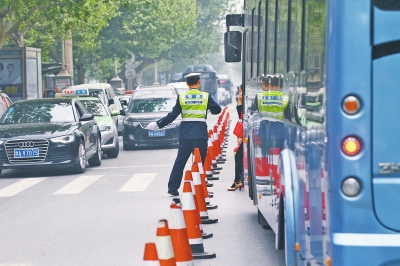 省人民醫(yī)院南門的路中間擺放反光錐，交警示意由西向東車輛從前方繞行。