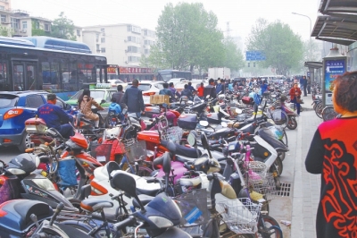 省人民醫(yī)院北門，路邊的公交站牌處停滿非機動車，上、下客只能在快車道上。