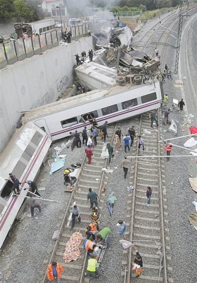 24日，救援人員在西班牙列車脫軌現(xiàn)場(chǎng)。一節(jié)車廂被強(qiáng)大的慣性拋上鐵道邊的高臺(tái)。