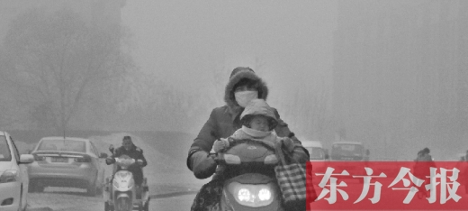 12月8日，鄭州市未來路上，一位市民帶著孩子在霧中騎行