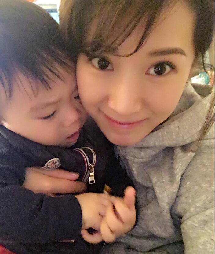 照片中李念狂吻兒子，小寶貝自顧自地玩著。