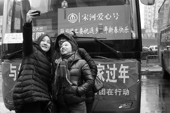 昨天上午8時，鄭州正道中環(huán)百貨廣場，準(zhǔn)備回家的老鄉(xiāng)在愛心大巴車前合影留念