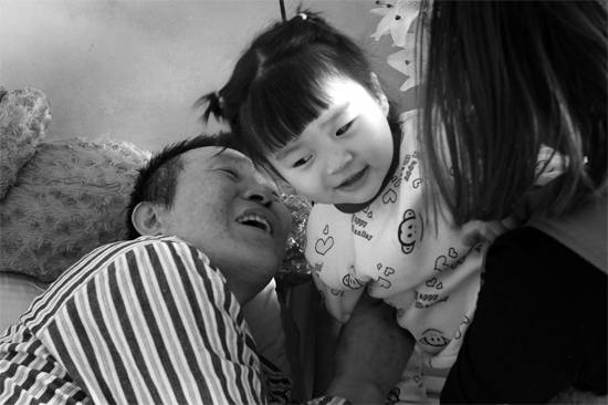 病床前李剛父女倆說(shuō)著“悄悄話”，幸福的氣氛洋溢在病房中