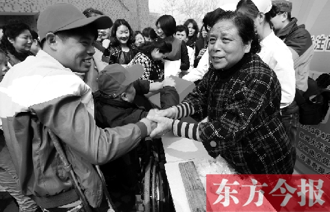 昨日，鄭大四附院的大樓前，“面人鄭”鄭玉芬（右）向前來捐款的殘疾人表示感謝