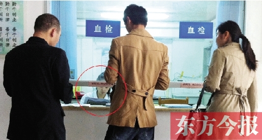 昨日，鄭州市二七區(qū)疾控中心辦證大廳，血檢窗口內(nèi)一名女工作人員，邊接受辦證者咨詢邊看報紙