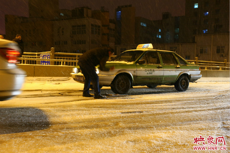 一位出租車司機(jī)在車輪前灑上雪，希望能增加輪胎的摩擦力。
