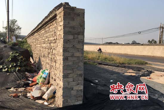 一墻之隔，一邊是道路，一邊是垃圾和荒草，市民質(zhì)疑其為遮羞墻。