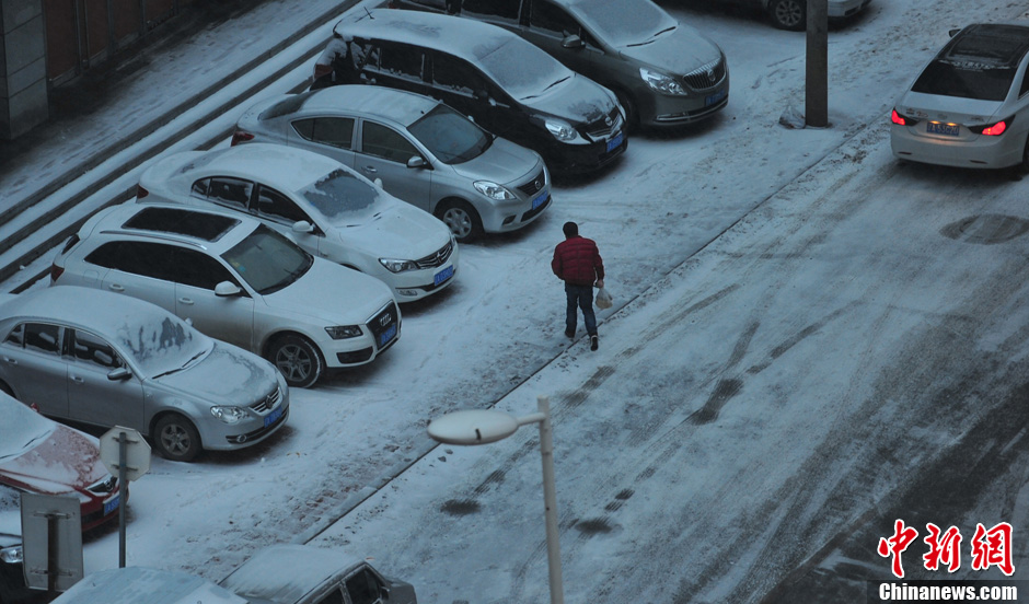 11月18日，行人在沈陽(yáng)街頭的積雪中穿行。