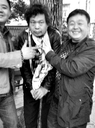 兩名接訪人員與患有癌癥的訪民段新德合影時，面帶笑容擺出勝利的手勢。