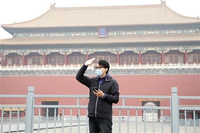 11月1日，北京大部分地區(qū)重度污染，一名游客戴著口罩在午門前揮手跟朋友打招呼。 實(shí)習(xí)生 王飛 攝