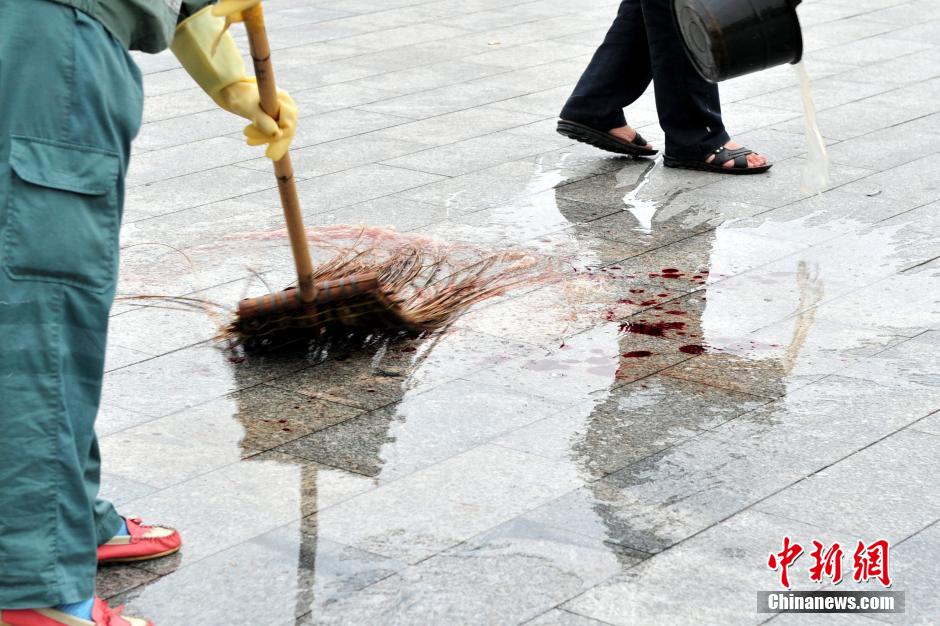 圖為環(huán)衛(wèi)工人在清理案發(fā)地點(diǎn)的血跡。