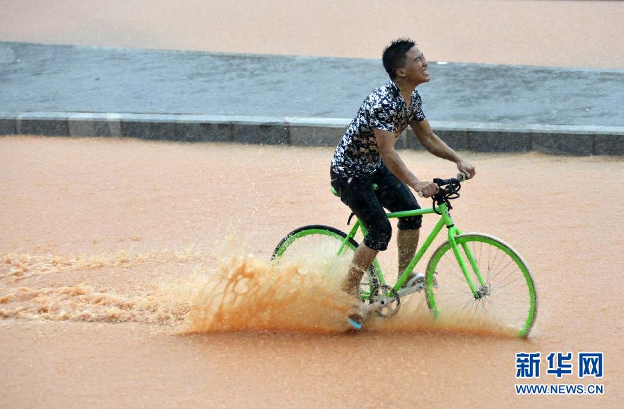 5月11日，一名行人在深圳街頭冒雨騎行。