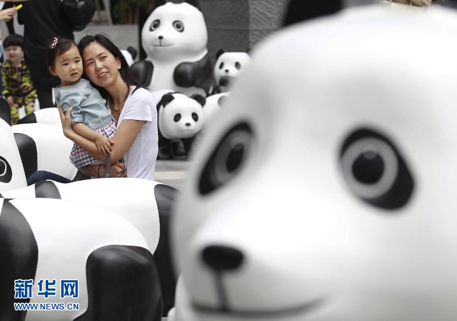6月2日，一位家長(zhǎng)帶著孩子在上海街頭和大熊貓模型合影。