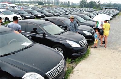 昨日，市民在山東棗莊一家拍賣公司場地上查看待拍賣公車。當(dāng)日，棗莊市103輛公車公開拍賣。新華社記者