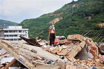 8月9日,龍頭山鎮(zhèn),一位老者在自家房屋廢墟上尋找家當(dāng)。