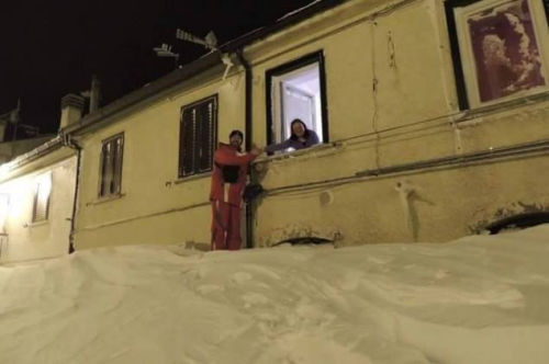 一個(gè)居民站在積雪上，可以與一名二樓鄰居在窗口握手。（來源：意大利氣象局）