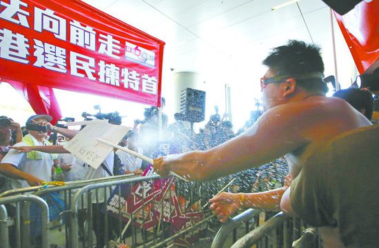 17日，在香港立法會(huì)外，一名反對政改的男子向支持派人群投擲標(biāo)牌。