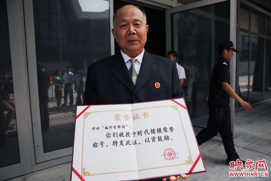 河南鄧州“編外雷鋒團(tuán)”團(tuán)長宋清梅向眾多記者展示中宣部授予的“時代楷?！睒s譽(yù)證書。