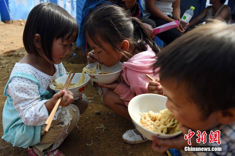 2014年8月6日，云南魯?shù)辇堫^山災(zāi)區(qū)，兒童在帳篷外吃飯。