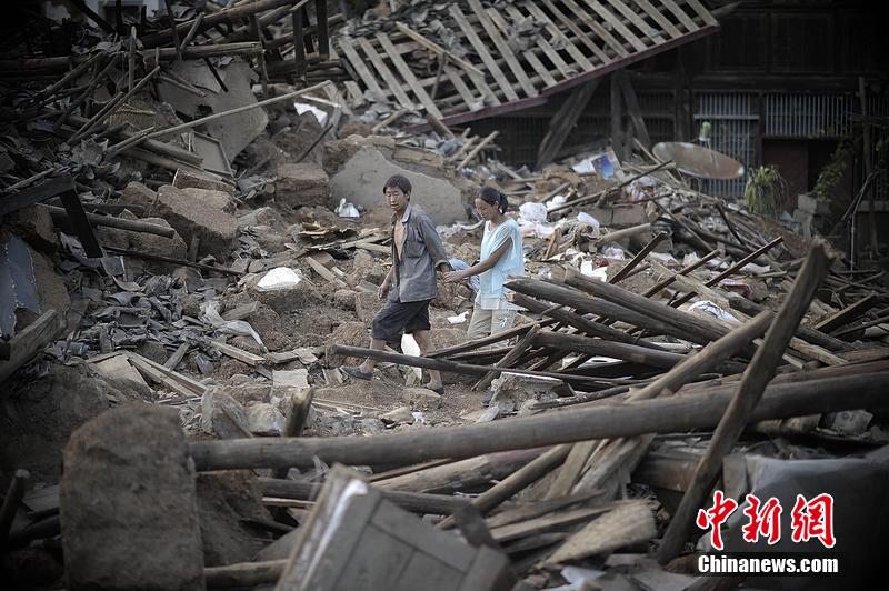 2014年8月5日，云南昭通龍頭山鎮(zhèn)老街，一對夫妻從居住房屋的廢墟中走過。