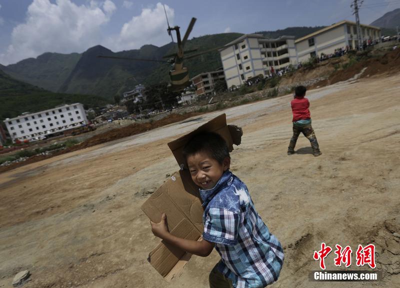 云南省昭通市魯?shù)榭h發(fā)生6.5級地震。幾個孩子在直升機降落的平地上玩耍。