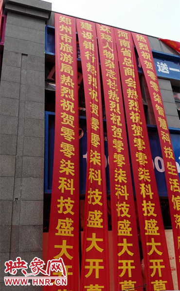 路邊一棟樓上懸掛著二三十條紅色條幅，全部是祝賀一家公司開業(yè)的。