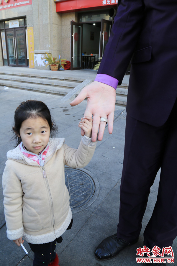 巨人“張歡”牽著一名漂亮的小女孩，兩人的手大小對比非常明顯。
