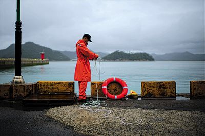 7月6日，韓國珍島，一名海岸警察在港口系救生圈。4月，客輪在珍島近海發(fā)生沉船事故后，仍有11人下落不明。