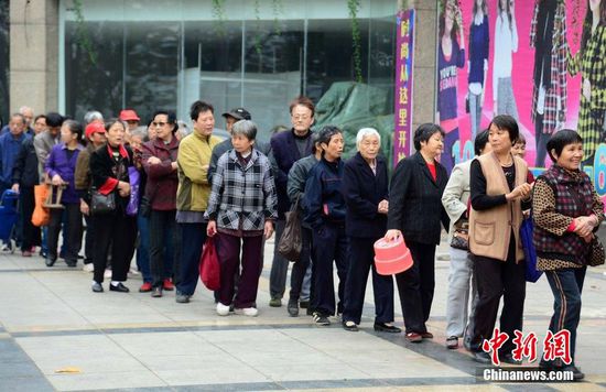 圖為10月28日，在江西九江市一家羊絨皮草服裝服飾博覽會現(xiàn)場，老人們正在頂著寒風排隊等待領取10元代金劵。