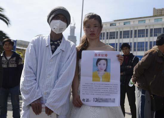 昆明火車站廣場(chǎng)上，24歲的黃習(xí)菊身穿潔白的婚紗，帶著身患白血病的弟弟征婚。